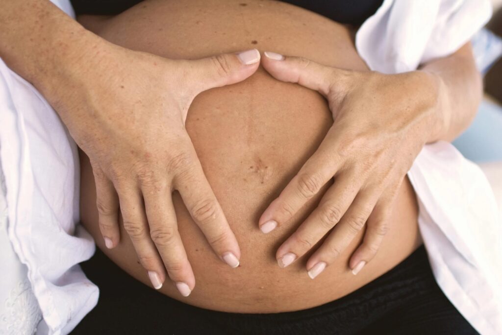 femme enceinte avec les mains sur le ventre dans une ambiance apaisante – soutien nutritionnel grossesse et post-partum